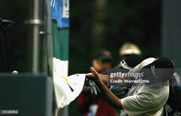 Wade Ormsby of Australia looks under a adervertising cloth after his ball lands in the public grandstand on the 18th green during the second round of...