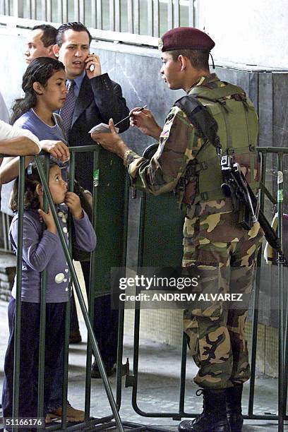 Un soldado da inicaciones a una mujer luego de revisar su documentacion en el Consejo Nacional Electoral , en Caracas, el 13 de agosto de 2004. Desde...