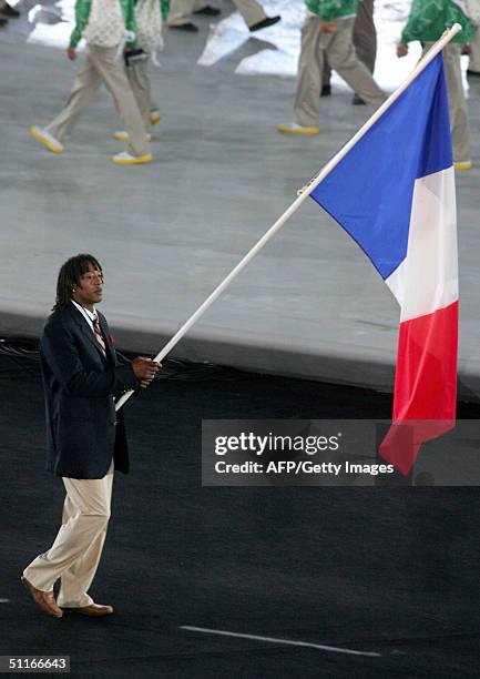 French handball competitor Jackson Richardson carries his country's flag at the opening ceremony of the 2004 Olympic Games at the Olympic stadium in...