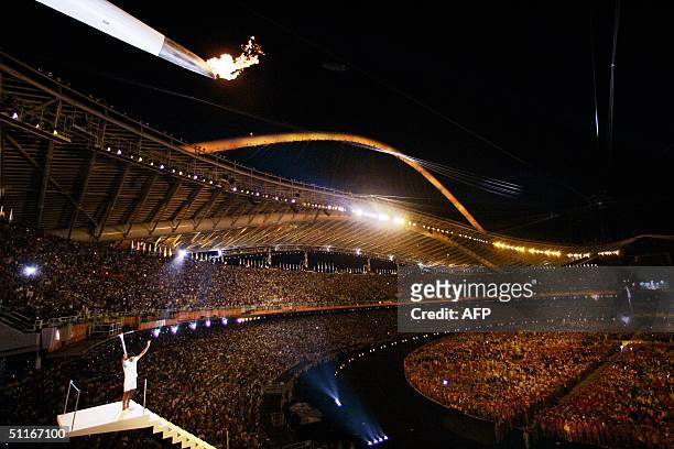 Olympic sailing mistral gold medalist Nikolaos Kaklamanakisstands under the Olympic cauldron after lighting it at the Olympic stadium during the...