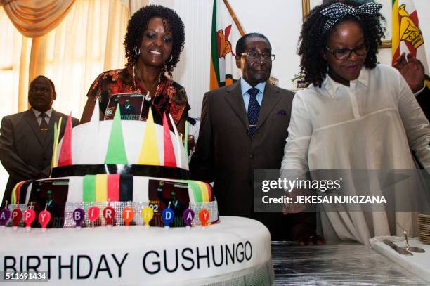 Zimbabwe President Robert Mugabe , flanked by his wife Grace Mugabe and daughter Bona , stand beside a cake adorned with the name of the Gushungo...