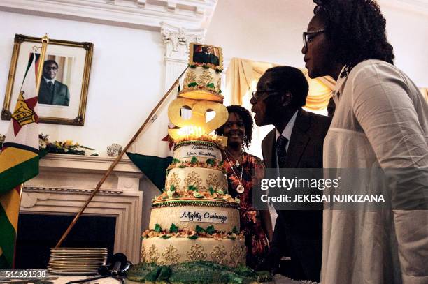 Zimbabwe President Robert Mugabe , flanked by his wife Grace Mugabe and daughter Bona , blows candles on his cake during a suprise party hosted by...