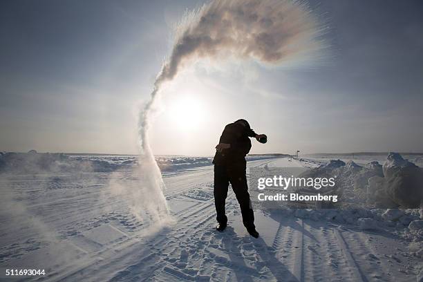 Man demonstrates the instant freezing of water in sub-zero temperatures as he stands on the ice road across the Lena River in Yakutsk, Sakha...
