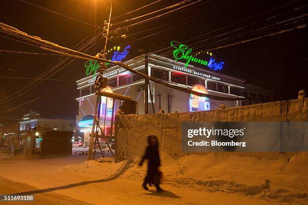 Resident walks along a snow covered road past the neon signs of the 'Europe' night club in Yakutsk, Sakha Republic, Russia, on Wednesday, Feb. 17,...