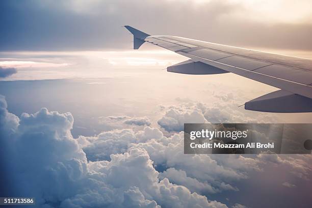 image of airplane wing flying above the clouds - plane stockfoto's en -beelden