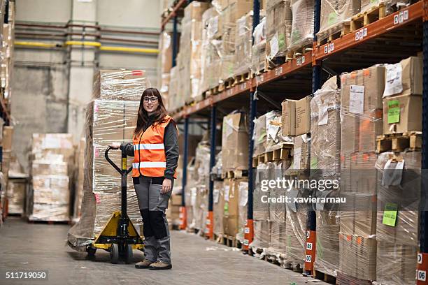 portrait woman moving boxes in a warehouse - pallet jack stock pictures, royalty-free photos & images