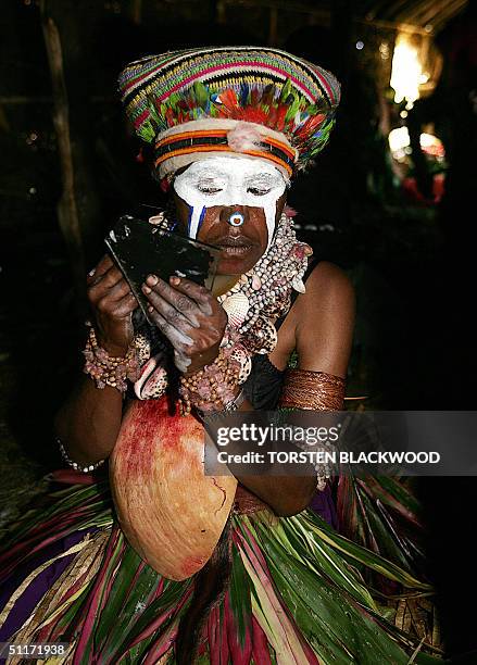 An Anda Kel Kang woman applies "White-Out" correction fluid as face paint in the dressing hut during the annual sing-sing cultural festival in Mount...