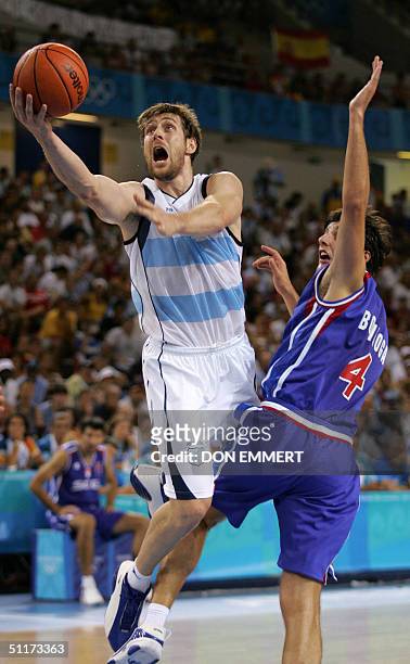 Argentina's Andres Nocioni takes a shot while being covered by Serbia and Montenegro's Dejan Bodiroga 15 August, 2004 during the Olympic Games Men's...