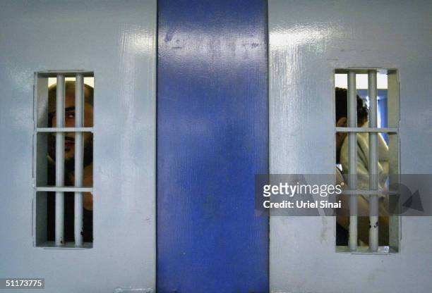 Palestinian security prisoners stand at the bars of their jail cells at the start of their hunger striket Hadarim Prison August 15, 2004 near Tel...