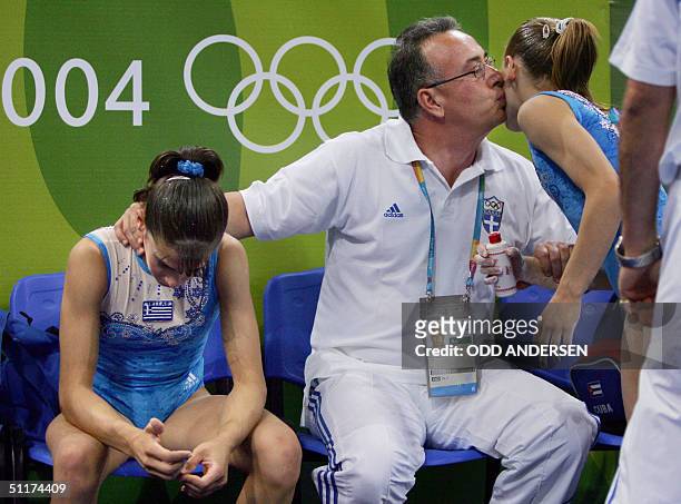 Greek gymnasts Maria Apostolidi and Stefani Bismpikou are comforted by a team member after performing in the women's Artistic Gymnastics...