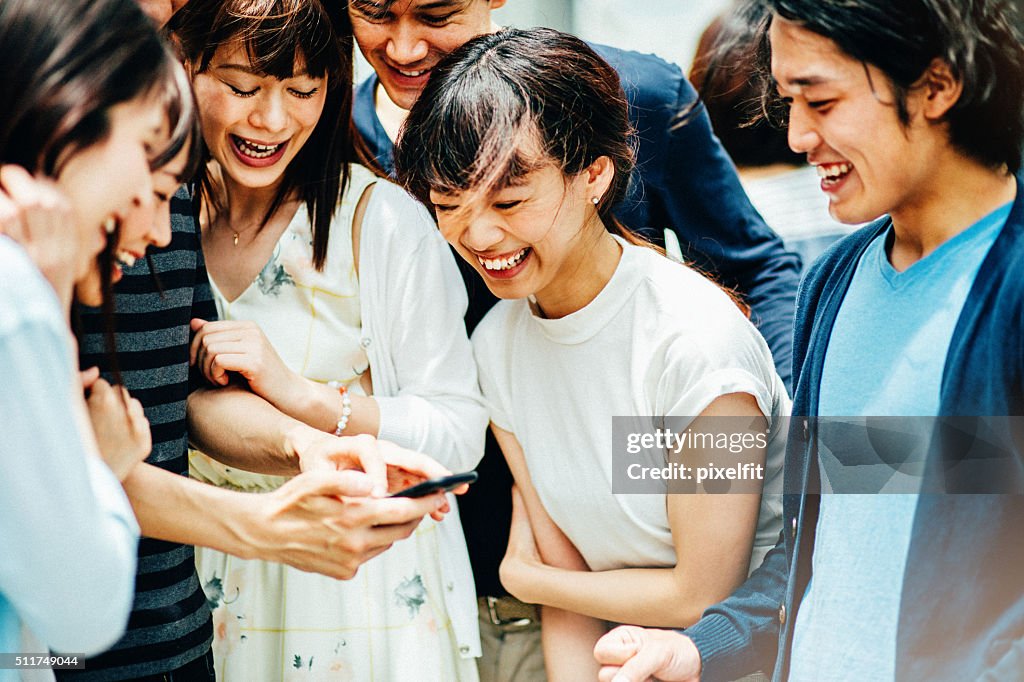 のグループ若いアジア人の友人にスマートフォン