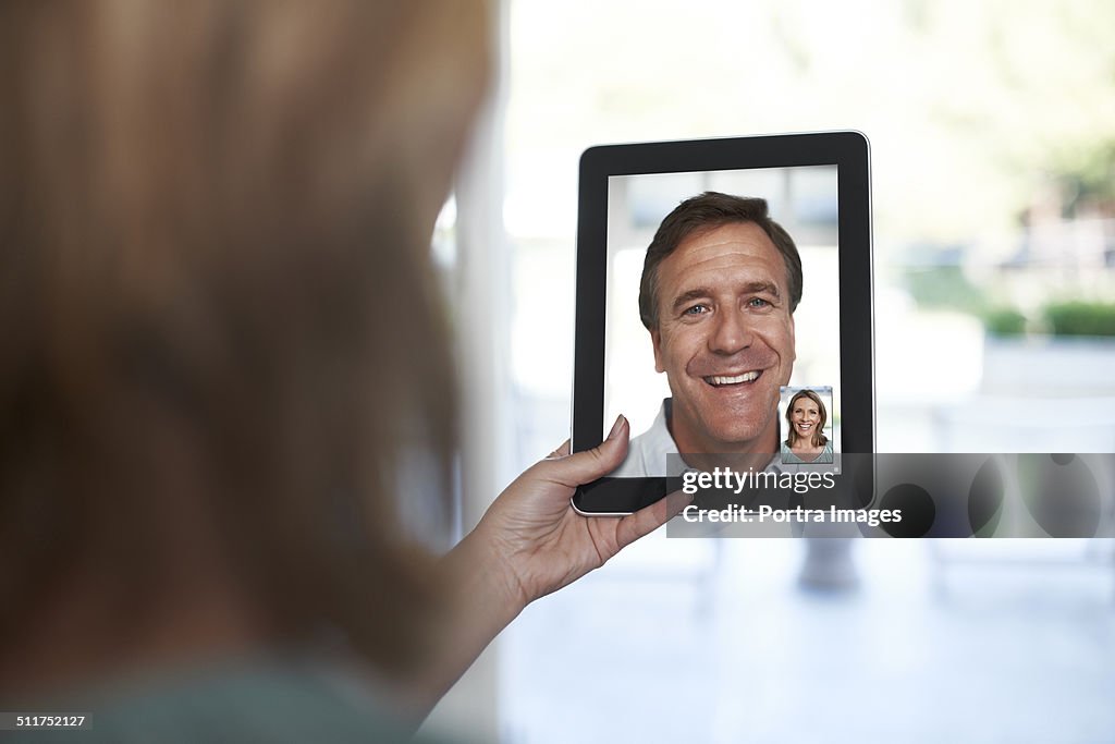 Woman video chatting with man on tablet PC