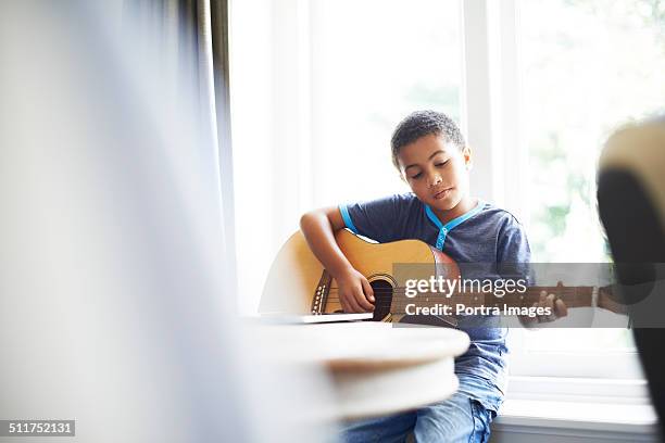 boy playing guitar at home - saiteninstrument spielen stock-fotos und bilder