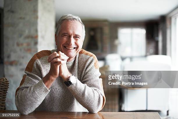 senior man with hands clasped in house - uomo anziano felice foto e immagini stock
