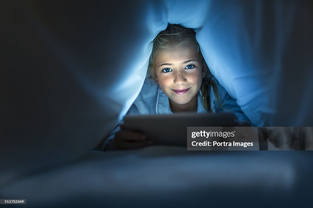 Girl using digital PC under blanket