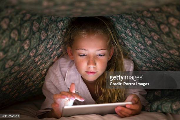 girl using digital tablet under blanket - ipad glow foto e immagini stock