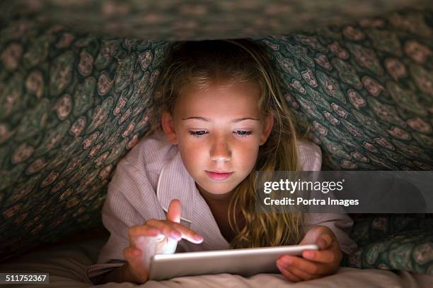 girl using digital tablet under blanket - rapariga no quarto tecnologia imagens e fotografias de stock