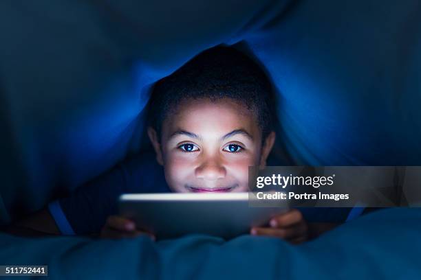 little boy using digital tablet under blanket - boy using ipad imagens e fotografias de stock