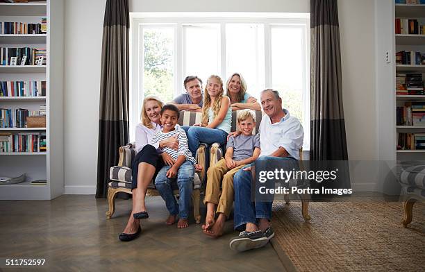 multi-ethnic family smiling in house - portrait of family sitting on sofa together stock pictures, royalty-free photos & images