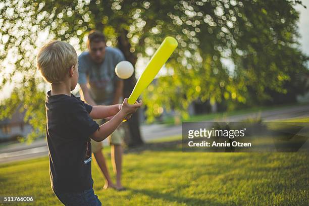 father and son playing baseball - baseball swing stock-fotos und bilder