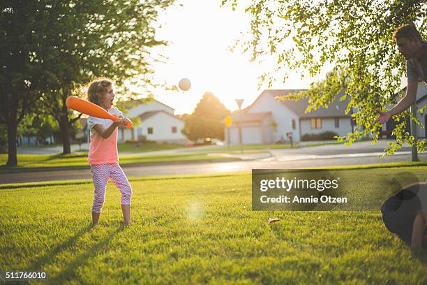 little girl playing baseball with her father - family garden play area stock pictures, royalty-free photos & images