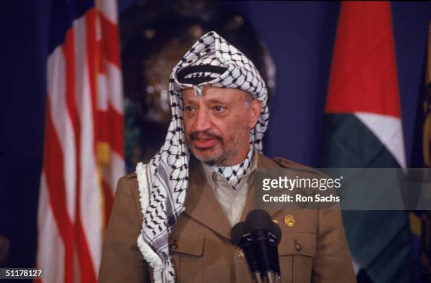 President of the Palestinian Authority and Chairman of the Palestine Liberation Organisation Yasser Arafat wears a traditional Arab headscarf and a...