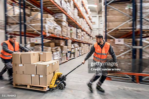 workers transporting boxes in warehouse - pulling stock pictures, royalty-free photos & images