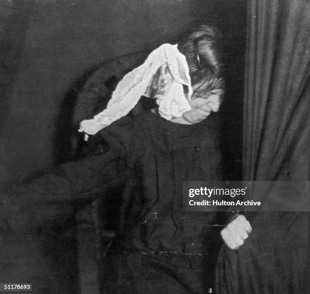 Strange visage appears on a piece of cloth next to the head of medium Marthe Beraud during a seance, circa 1910. Picture taken from 'Les Phenomenes...