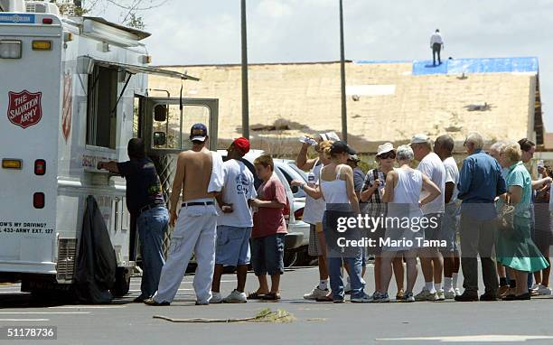 Residents line up for donated goods from a Salvation Army truck in front of a damaged church August 16, 2004 in Port Charlotte, Florida. Hurricane...