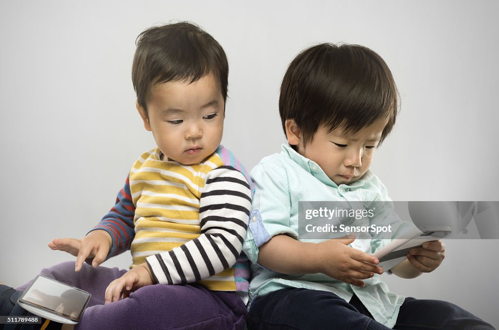 Portrait of two japanese kids with their electronic devices.