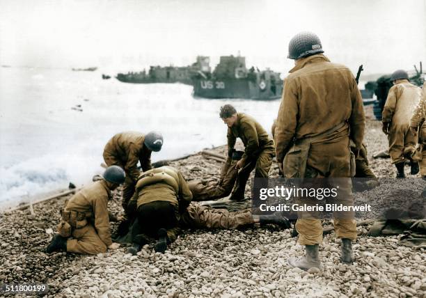 Operation Overlord - On a pebble beach at Omaha Beach U.S. Soldiers deal with injuries. 6th June 1944. All these men are from the 5th or 6th Engineer...