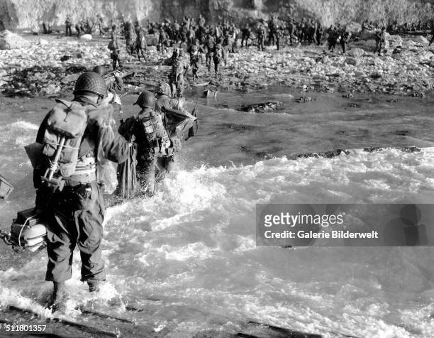 Troops of the 5th Engineer Special Brigade, wade through the surf at at Fox Green, Omaha Beach. 8th June 1944. They are part of the invasion forces....