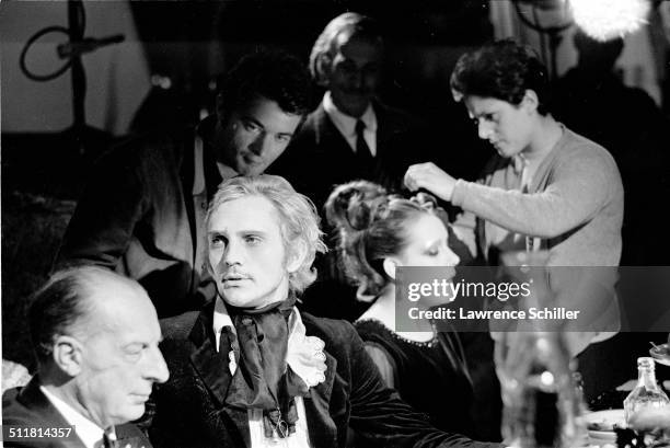 British actor Terence Stamp and others sit at a table during production of 'Toby Dammit' , one section of the anthology film 'Spirits of the Dead,'...