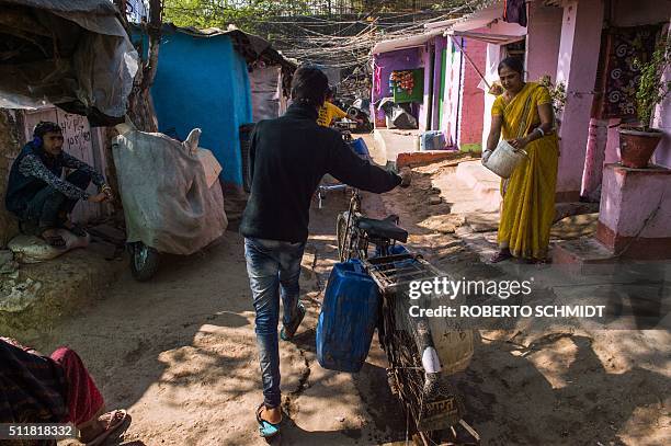 Resident of the eastern New Delhi neighborhood of Sanjay Camp pushes a bicycle loaded with water containers as he heads home after collecting the...