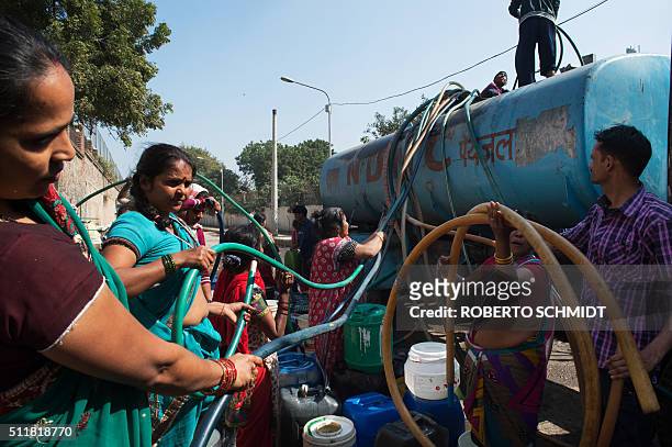 Indian residents remove hoses from a water distribution truck at a distribution point in the low-income eastern New Delhi neighborhood of Sanjay camp...