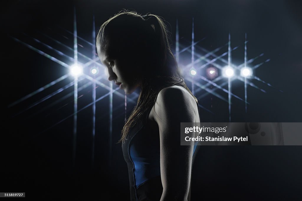 Portrait of female athlete, stadium lights behind
