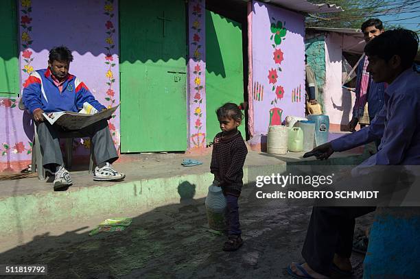 An Indian girl struggles to carry a jerry can filled with water as she helps family members fetch water from a distribution point in the low-income...