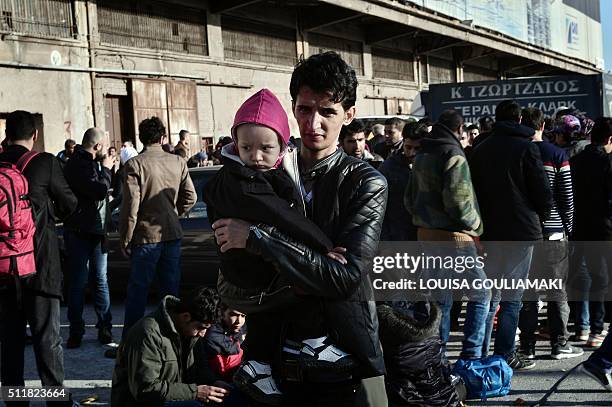 Migrants and refugees queue to receive food distributed by a NGO at the port of Piraeus on February 23, 2016 after their arrival from the Greek...