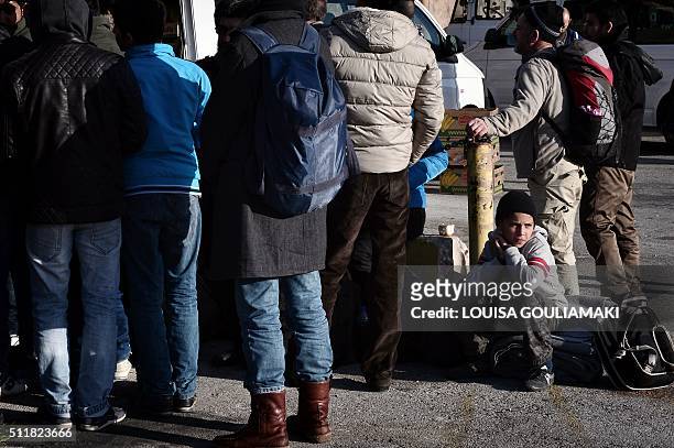 Migrants and refugees queue to receive food distributed by a NGO at the port of Piraeus on February 23, 2016 after their arrival from the Greek...