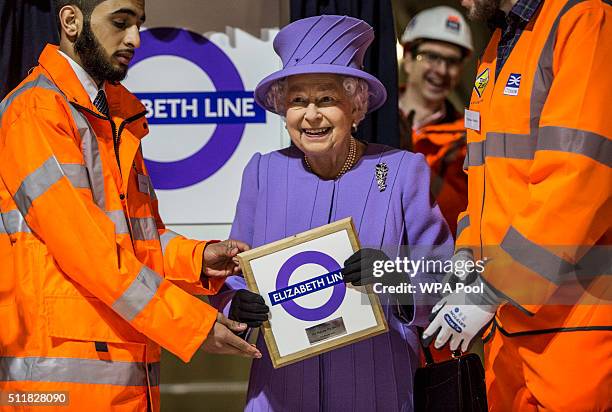 Queen Elizabeth holds a commemorative plaque given to her by Crossrail workers after she formally unveiled the new roundel for the Crossrail line...