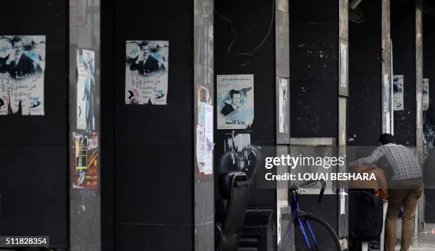 Syrians stand next to columns on which posters bearing a portrait of Syrian President Bashar al-Assad are displayed in the capital Damascus on...