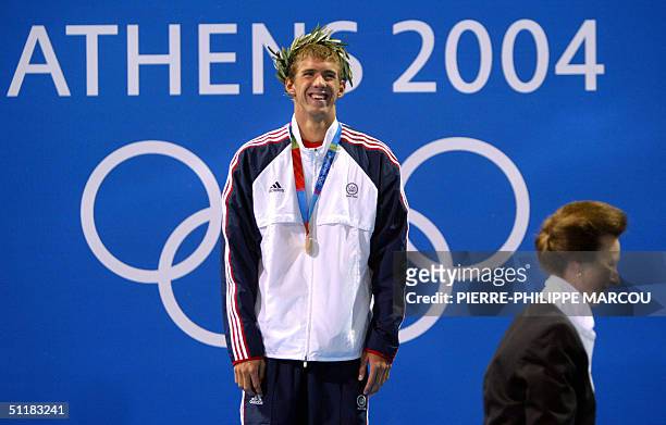 Gold medallist Michael Phelps celebrates on the podium of the men's 200m butterfly final as the Princess Ann smiles at the 2004 Olympic Games at the...