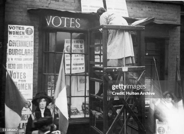 English suffragette Estelle Sylvia Pankhurst stands on a platform to paint the front of the Women's Social Defence League premises in Bow Road, East...