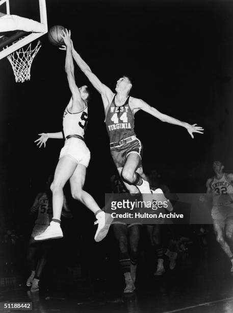 The University of West Virginia's Jerry West soaring through the air to prevent the University of Kentucky's Adrian Smith from making a lay-up during...