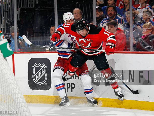 Tanner Glass of the New York Rangers checks Stephen Gionta of the New Jersey Devils during the first period at the Prudential Center on February 23,...