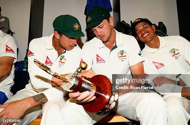 James Pattinson, Josh Hazlewood and Usman Khawaja of Australia celebrate with the Trans-Tasman Trophy in the change rooms after day five of the Test...