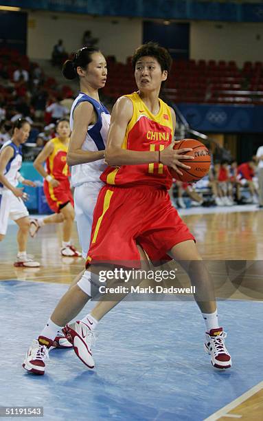 Le Yi of China is defended by a player from Korea in the women's basketball preliminary game on August 14, 2004 during the Athens 2004 Summer Olympic...