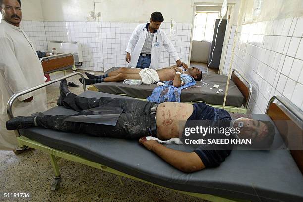 Doctor attends to critically injured Iraqi policemen inside an emergency room of Najaf's al-Hakim hospital 19 August 2004 after mortar bombs smashed...