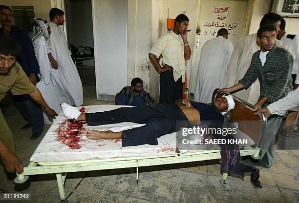 Relatives shift an injured Iraqi policeman to a ward from an emergency room of Najaf's al-Hakim hospital 19 August 2004 after mortar bombs smashed...