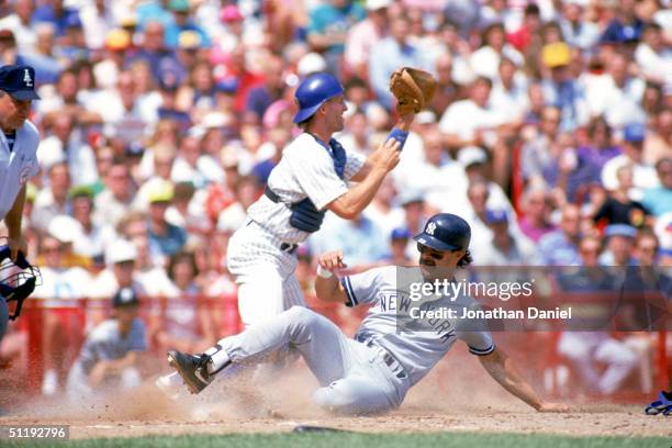 Don Mattingly of the New York Yankees slides safely at home plate past catcher B.J. Surhoff of the Milwaukee Brewers during a 1990 season game at...